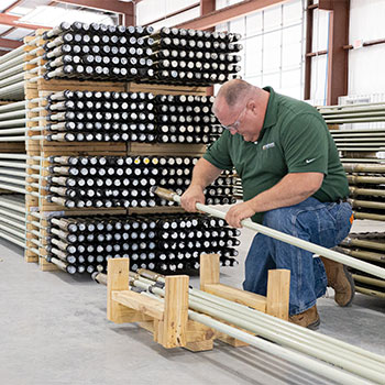 An Endurance Lift employee working with fiberglass sucker rods.